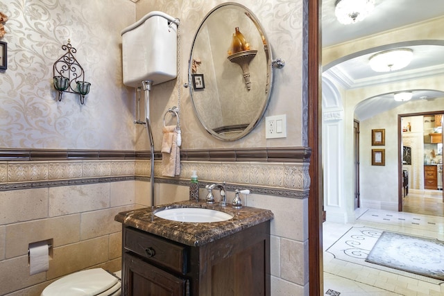 bathroom featuring ornamental molding, a wainscoted wall, vanity, and wallpapered walls