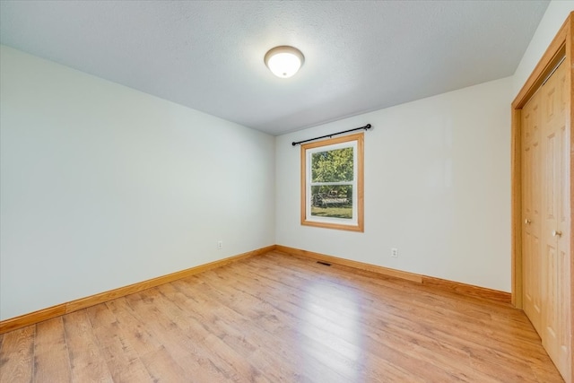 unfurnished bedroom featuring a textured ceiling, a closet, and light hardwood / wood-style floors