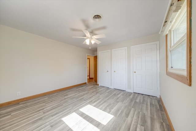 unfurnished bedroom featuring ceiling fan, multiple closets, and light hardwood / wood-style floors