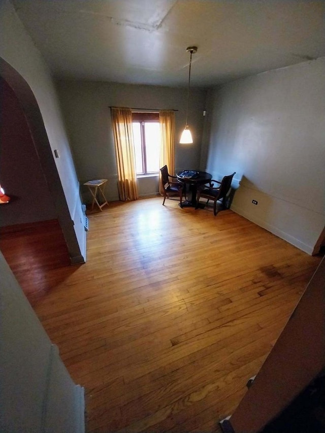 dining area featuring arched walkways and wood finished floors