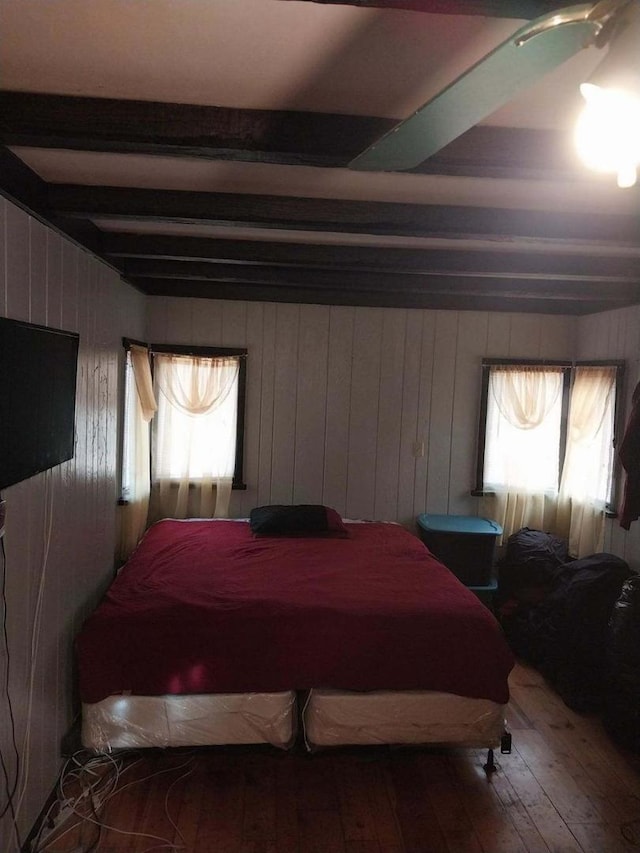 bedroom featuring ceiling fan, beamed ceiling, and hardwood / wood-style floors