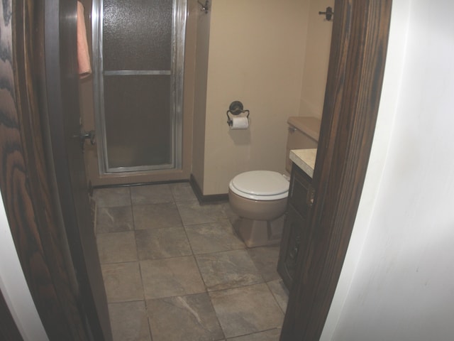 bathroom featuring a shower with door, toilet, vanity, and tile patterned floors