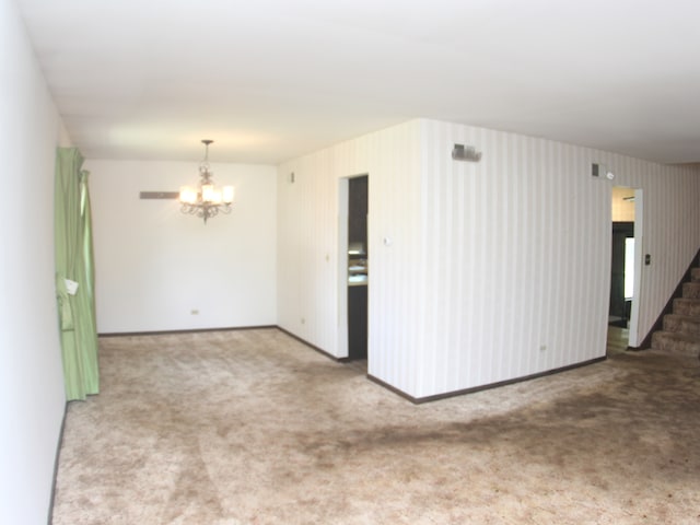 empty room with carpet flooring and a chandelier