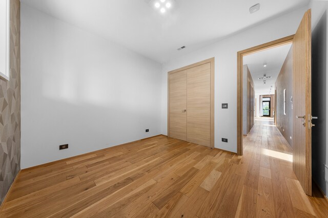 unfurnished bedroom with light hardwood / wood-style floors and a closet