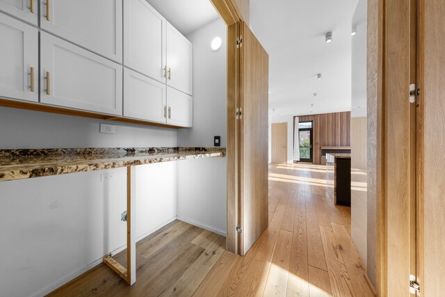 interior space with stone countertops, white cabinetry, and light wood-type flooring