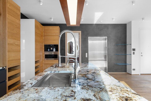 kitchen featuring light hardwood / wood-style floors, light stone countertops, and appliances with stainless steel finishes