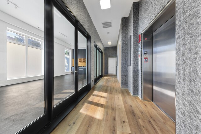 hall featuring a wealth of natural light, light hardwood / wood-style flooring, and elevator