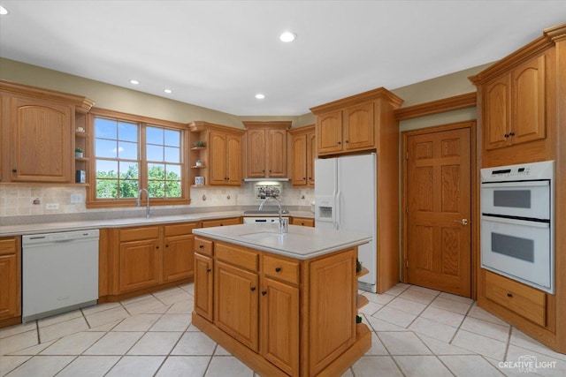 kitchen with white appliances, light tile patterned flooring, a kitchen island with sink, and tasteful backsplash