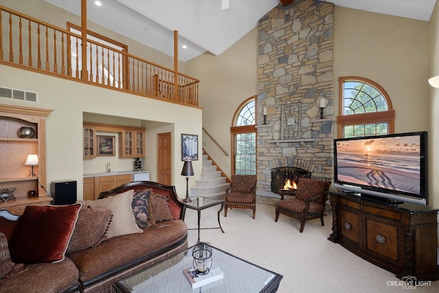 carpeted living room featuring a healthy amount of sunlight, vaulted ceiling, wet bar, and a fireplace