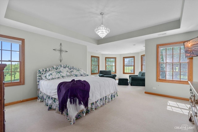 bedroom with a raised ceiling, light carpet, multiple windows, and an inviting chandelier