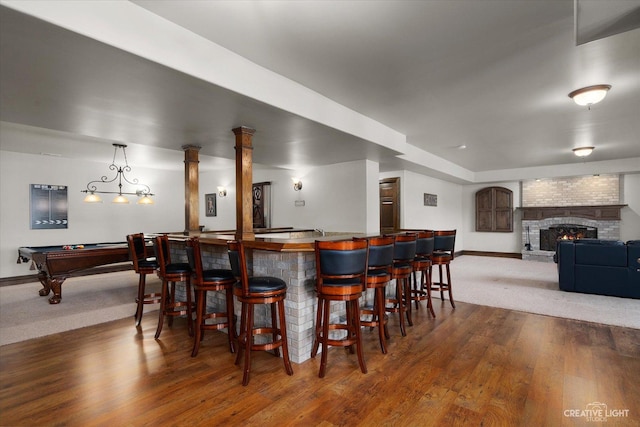 bar featuring a fireplace, hardwood / wood-style flooring, and pool table