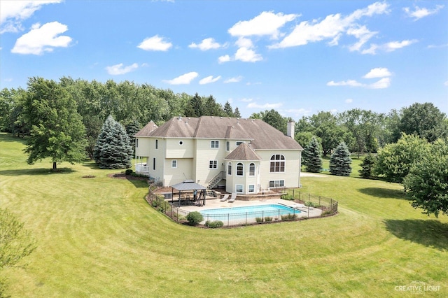 rear view of house with a yard, a fenced in pool, and a gazebo