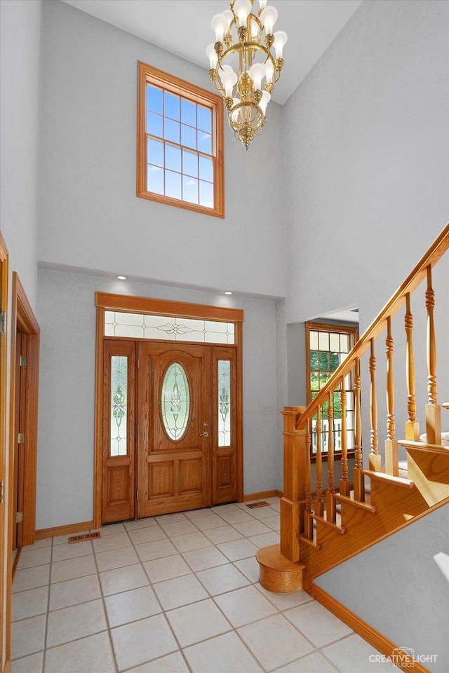 foyer featuring light tile patterned floors, an inviting chandelier, and a towering ceiling