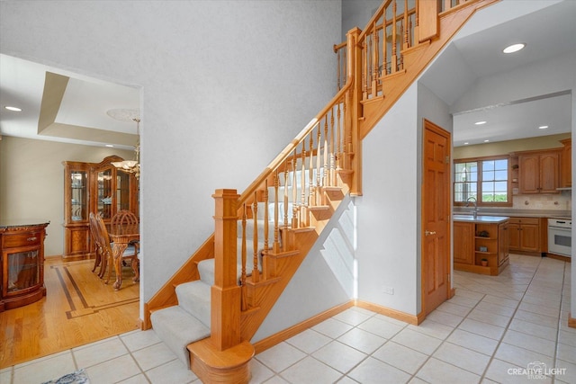 staircase featuring tile patterned floors, sink, and a notable chandelier