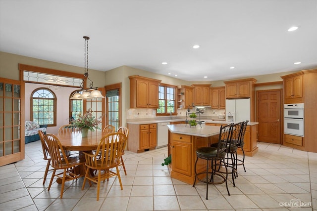 kitchen featuring light tile patterned floors, white appliances, decorative backsplash, pendant lighting, and a kitchen island