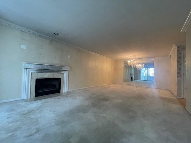 unfurnished living room with a tile fireplace, concrete floors, and a notable chandelier