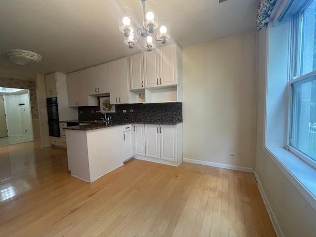 kitchen with light hardwood / wood-style flooring, white cabinets, a chandelier, and pendant lighting