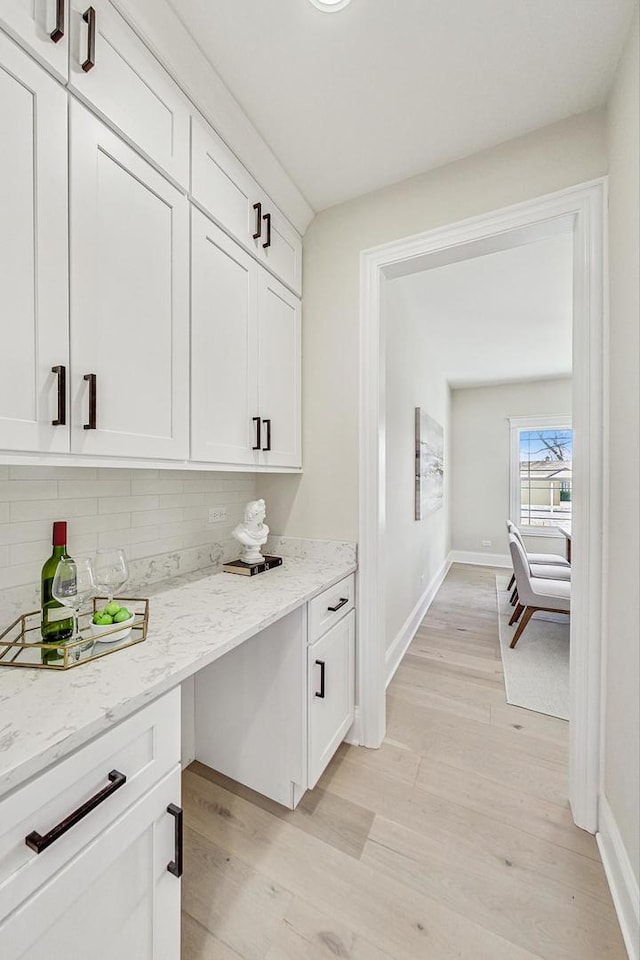 bar featuring baseboards, backsplash, and light wood-style floors