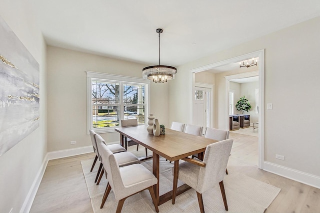 dining area with an inviting chandelier, baseboards, and light wood finished floors