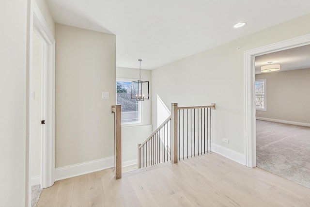 hallway with a notable chandelier, recessed lighting, wood finished floors, an upstairs landing, and baseboards