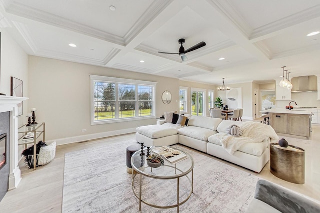 living room featuring beamed ceiling, coffered ceiling, and a glass covered fireplace