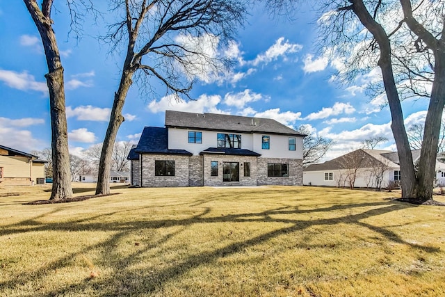 back of house featuring stone siding and a yard