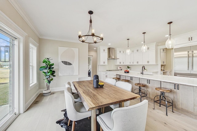 dining space with ornamental molding, a chandelier, baseboards, and light wood finished floors