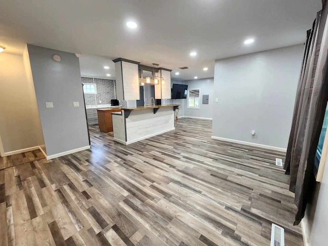 kitchen featuring sink, a breakfast bar area, hanging light fixtures, and light hardwood / wood-style flooring