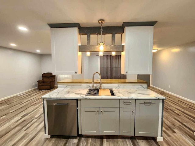 kitchen featuring light hardwood / wood-style flooring, pendant lighting, stainless steel dishwasher, and light stone countertops