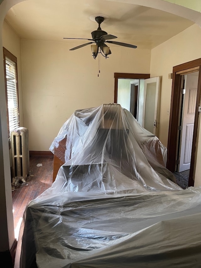 unfurnished bedroom with ceiling fan, dark hardwood / wood-style flooring, and radiator heating unit