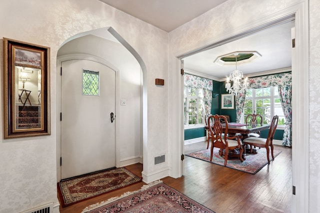 foyer entrance with dark hardwood / wood-style floors and an inviting chandelier