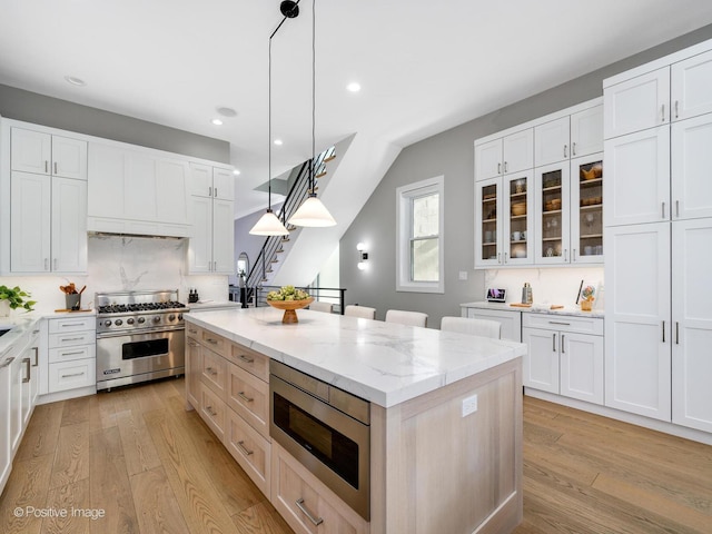 kitchen with stainless steel appliances, hanging light fixtures, and white cabinets