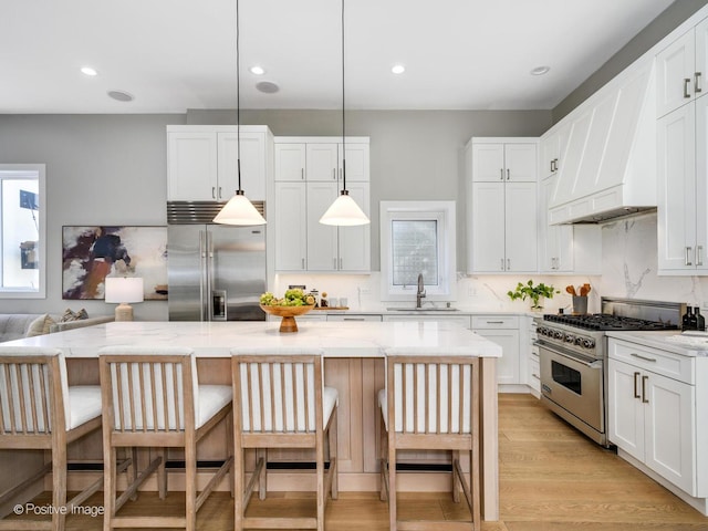 kitchen featuring premium appliances, hanging light fixtures, and a center island