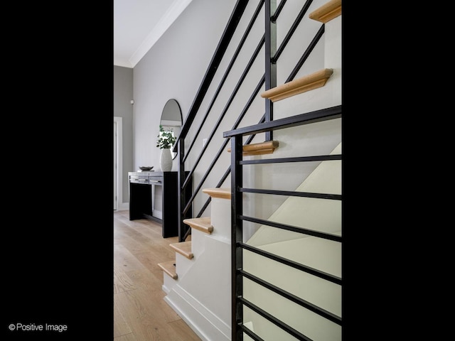 stairway with ornamental molding, hardwood / wood-style floors, and a high ceiling