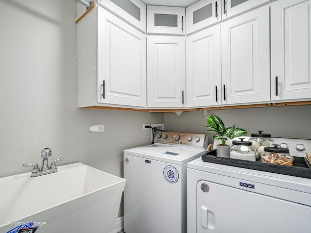 laundry area featuring separate washer and dryer, sink, and cabinets