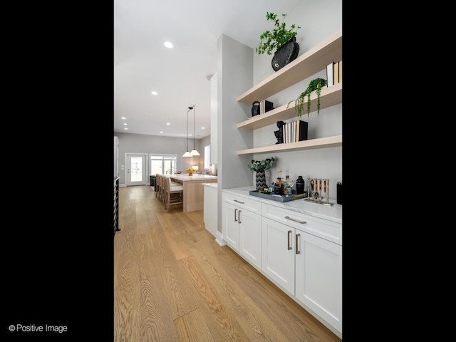 bar featuring pendant lighting, white cabinets, and light wood-type flooring