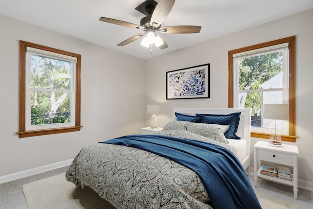 bedroom featuring multiple windows, light carpet, and ceiling fan