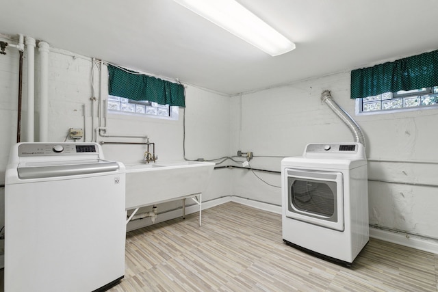 laundry room featuring sink, washer and dryer, and light wood-type flooring