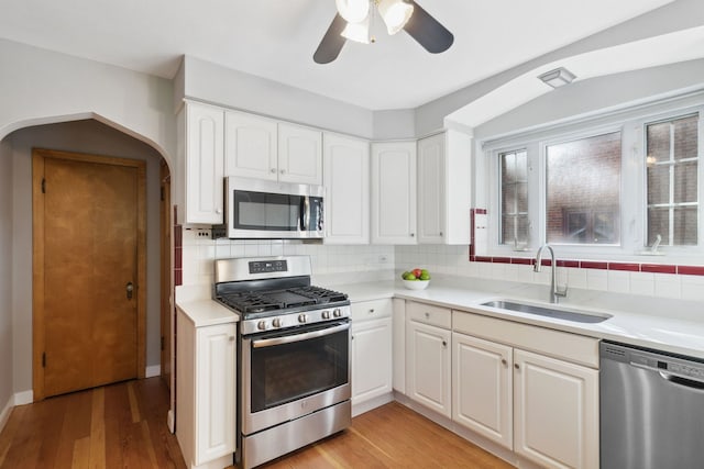 kitchen with white cabinets, appliances with stainless steel finishes, light hardwood / wood-style flooring, and sink