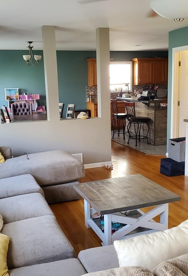 living room featuring sink, light hardwood / wood-style floors, and an inviting chandelier