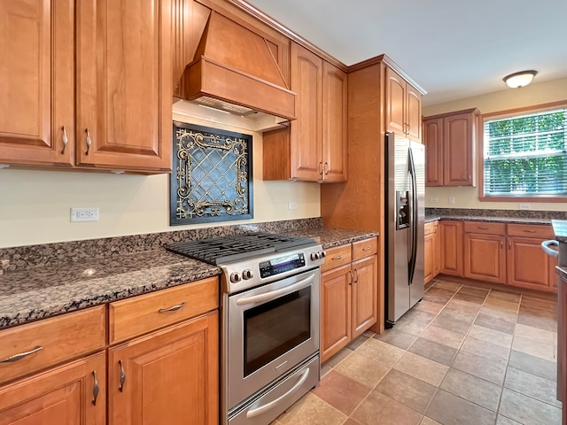 kitchen featuring stainless steel appliances, dark stone countertops, and premium range hood