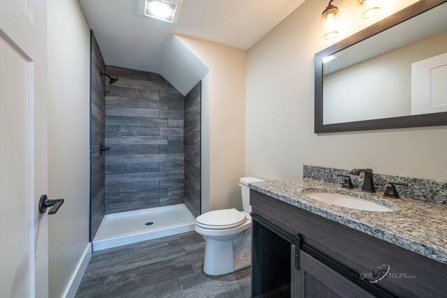 bathroom with tiled shower, hardwood / wood-style floors, vanity, and toilet