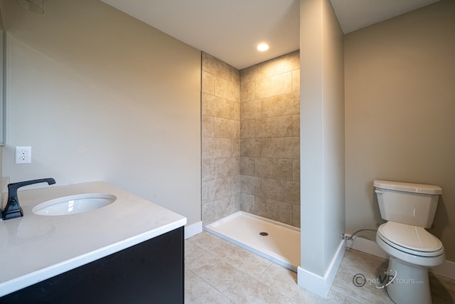 bathroom featuring tile patterned flooring, a tile shower, vanity, and toilet