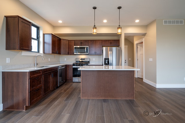 kitchen featuring dark wood-type flooring, sink, decorative light fixtures, a kitchen island, and stainless steel appliances