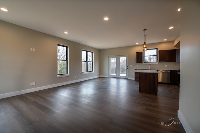 kitchen featuring a center island, sink, dark wood-type flooring, stainless steel dishwasher, and decorative light fixtures