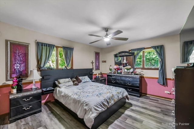 bedroom featuring multiple windows, hardwood / wood-style flooring, and ceiling fan