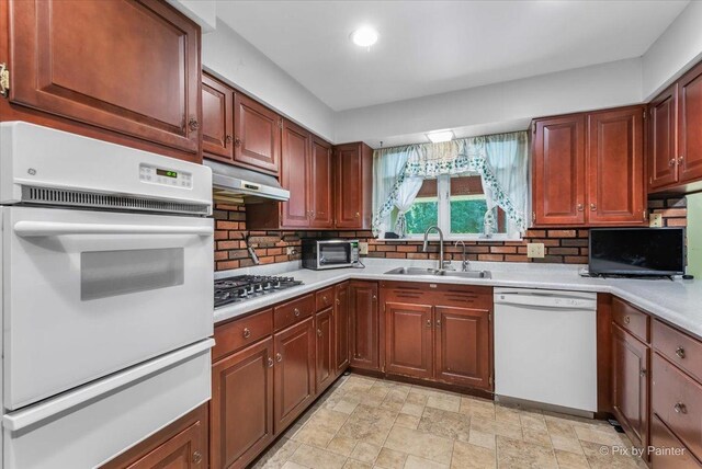 kitchen with sink, decorative backsplash, white appliances, and light tile patterned floors