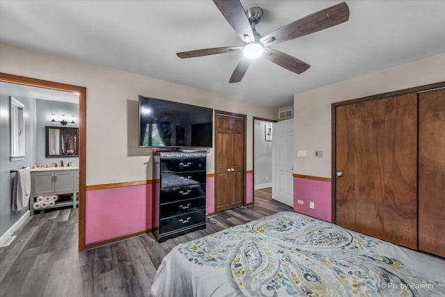 bedroom with ceiling fan, dark wood-type flooring, and ensuite bath