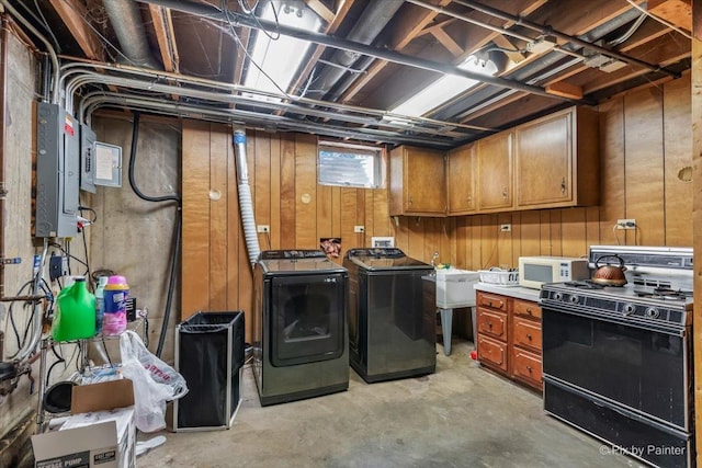 clothes washing area featuring cabinet space, wood walls, a sink, washer and dryer, and electric panel