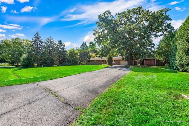 view of yard with aphalt driveway and a garage